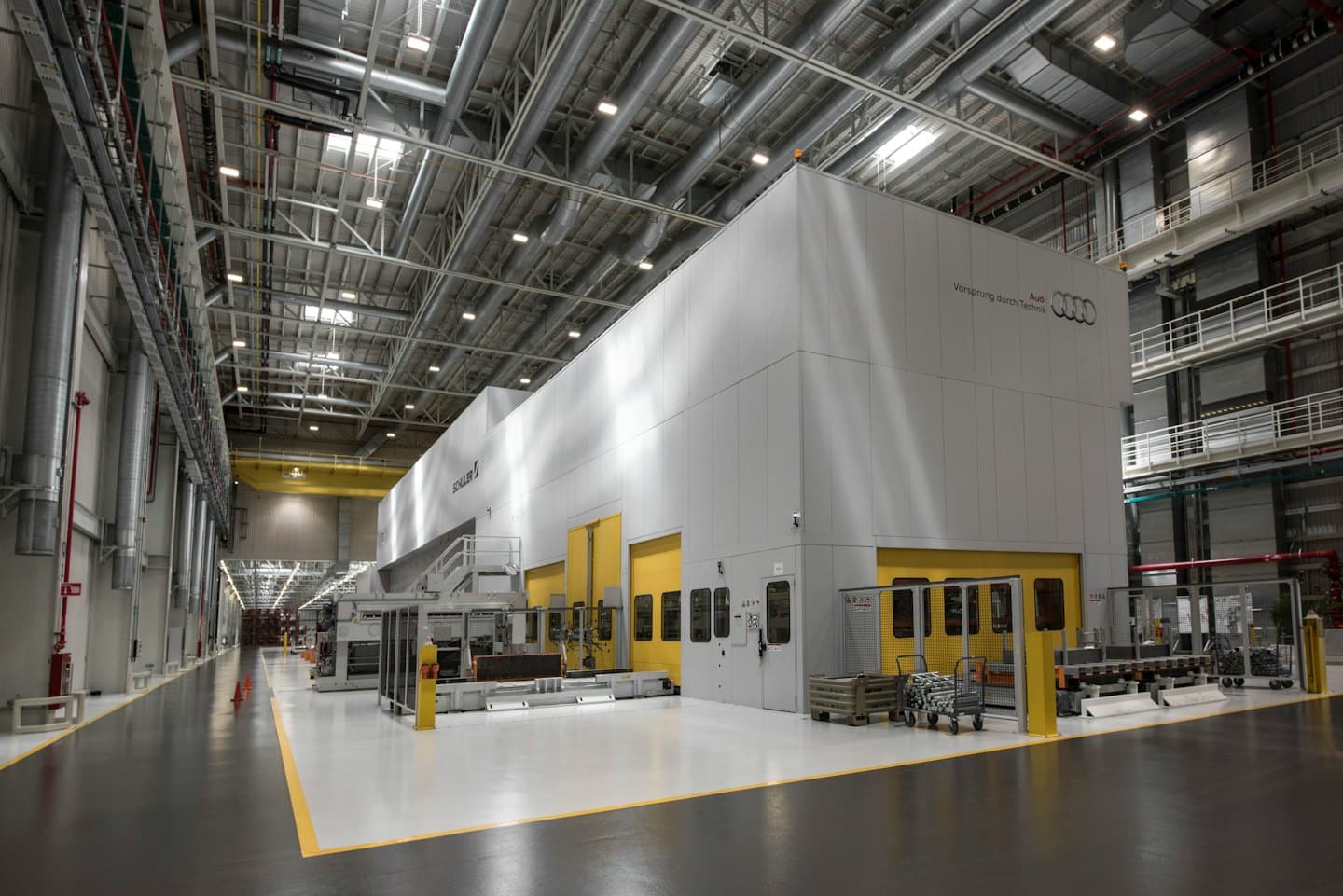 Modern factory floor with a large grey machine and yellow safety lines.